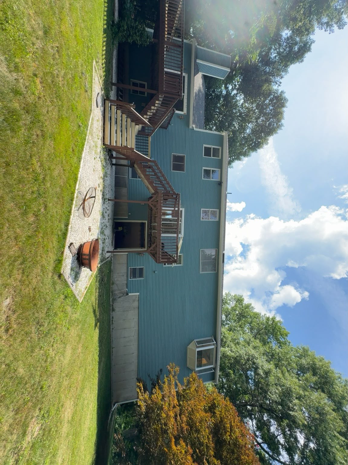 Large home with freshly painted blue siding, white trim and stained decks