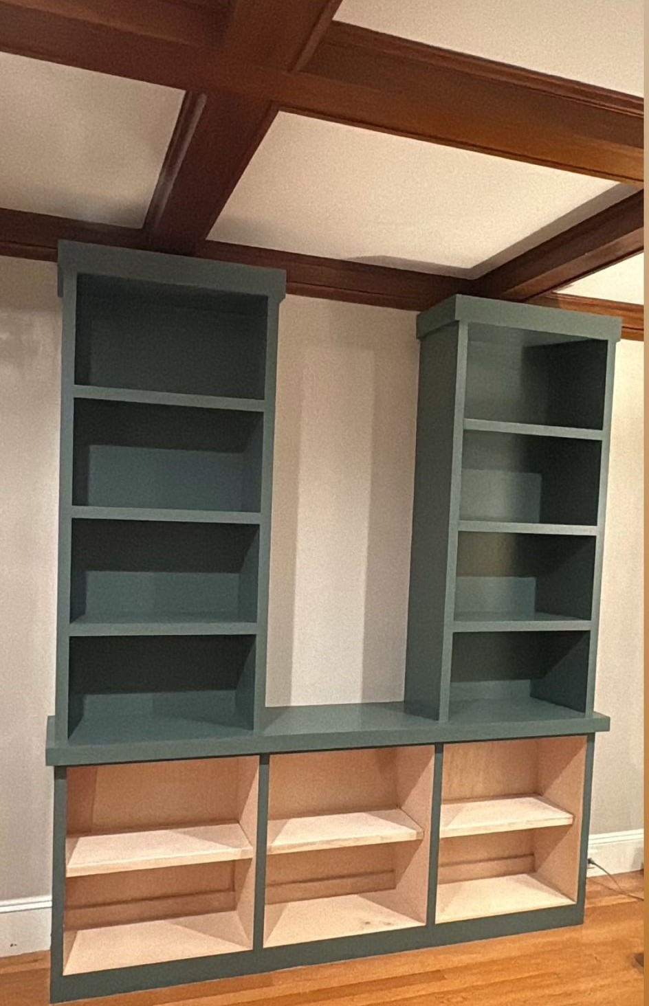 Custom built-in bookcase finished in a deep sage green with a smooth sprayed surface