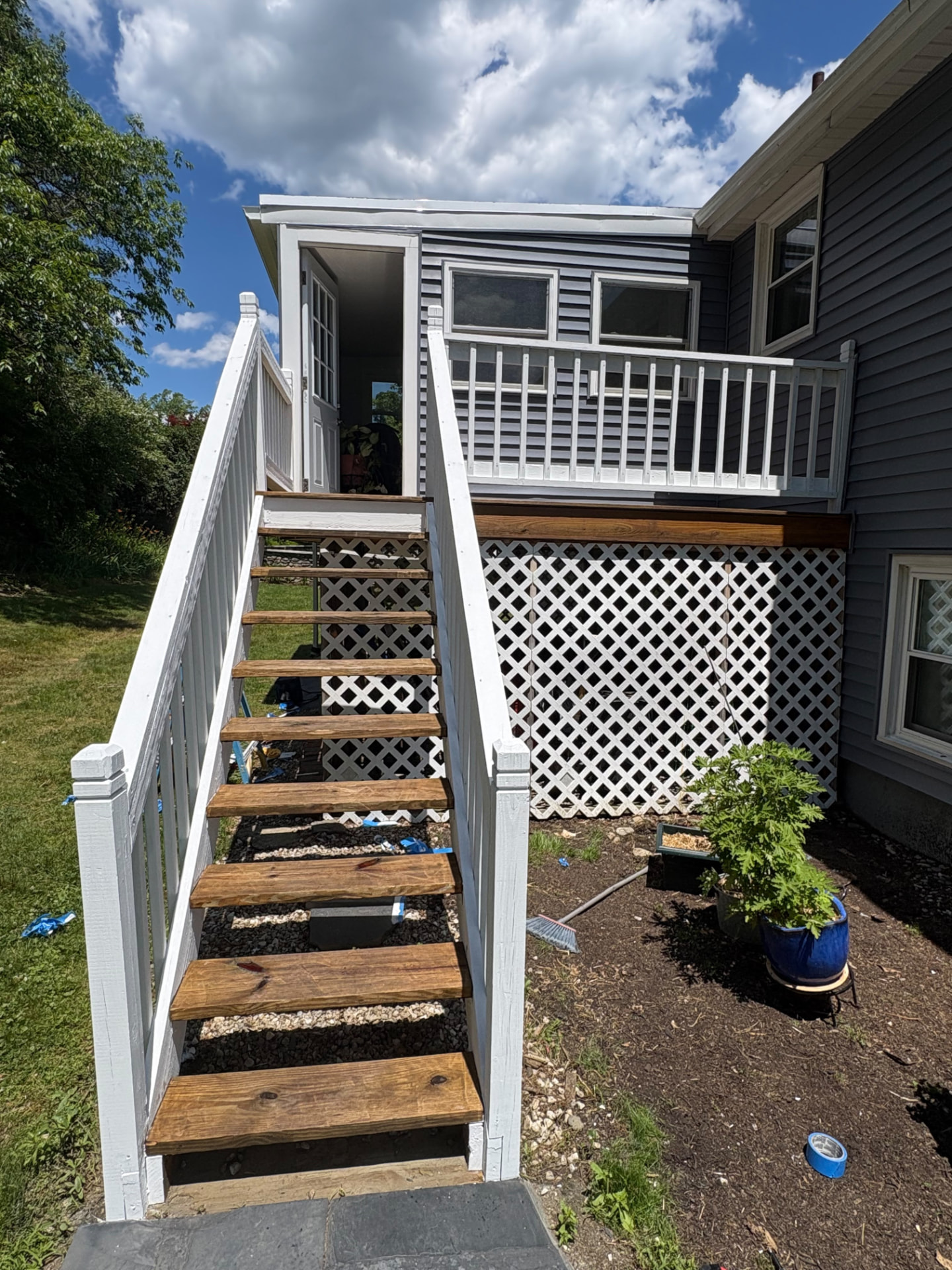 Exterior stairs and railings painted crisp white beside grey siding