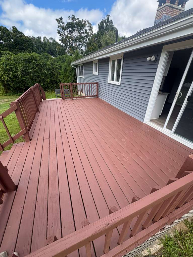 Backyard deck and railings finished in a rich red-brown stain beside grey siding